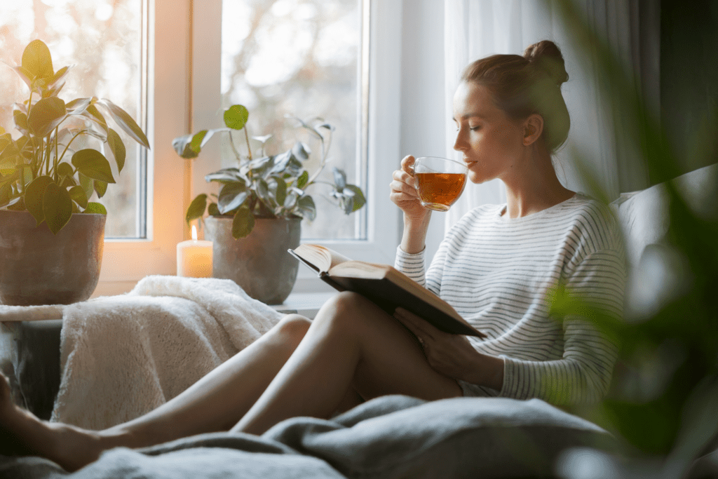 A woman wrapped in a cozy blanket enjoys a warm drink, symbolizing self-care, relaxation, and the soft life lifestyle.